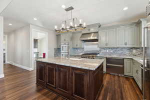 Kitchen featuring under cabinet range hood, double oven, dark wood-type flooring