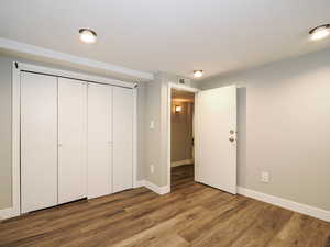 Unfurnished bedroom featuring baseboards, a closet, visible vents, and wood finished floors