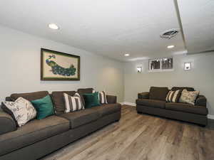 Living area featuring baseboards, visible vents, wood finished floors, a textured ceiling, and recessed lighting