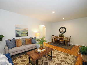 Living room with recessed lighting, arched walkways, baseboards, and wood finished floors