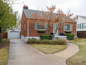 Bungalow-style house with driveway, a detached garage, an outbuilding, fence, and brick siding