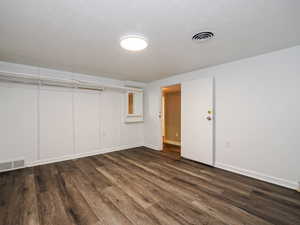 Basement featuring visible vents, baseboards, and wood finished floors