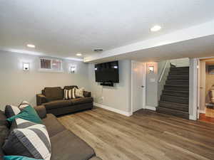 Living area with a textured ceiling, wood finished floors, and baseboards