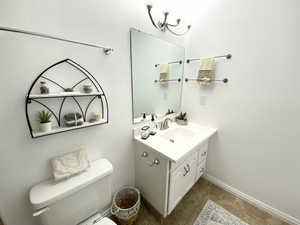 Bathroom featuring vanity, toilet, and baseboards