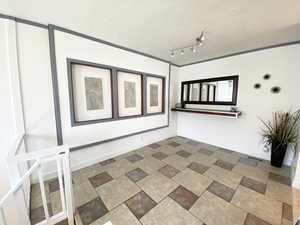 Empty room with rail lighting, stone finish flooring, visible vents, and baseboards