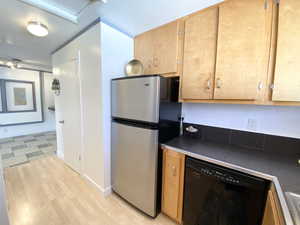 Kitchen featuring light floors, dishwasher, and freestanding refrigerator