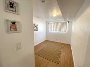 Empty room featuring visible vents, a textured ceiling, baseboards, and wood finished floors