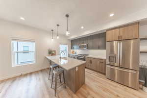 Kitchen featuring a breakfast bar with sink, quartz countertops, backsplash, appliances with stainless steel finishes. All kitchen appliances are included!