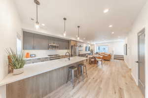 Kitchen with backsplash, modern cabinets, quarts countertops, appliances with stainless steel finishes, gray cabinets, and island bar sink