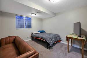 Carpeted bedroom with a textured ceiling, visible vents, and baseboards