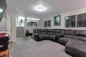 Living area with a textured ceiling, stairs, visible vents, and carpet flooring