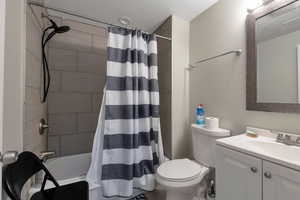 Bathroom featuring visible vents, toilet, shower / bath combo with shower curtain, a textured ceiling, and vanity