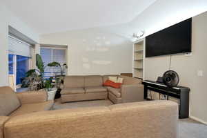 Carpeted living area with vaulted ceiling