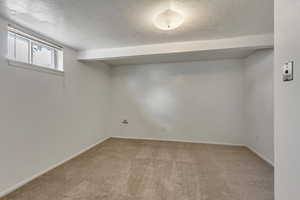 Basement featuring a textured ceiling, carpet flooring, and baseboards