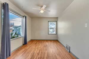 Unfurnished room with a ceiling fan, light wood-type flooring, visible vents, and baseboards