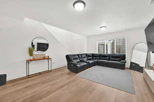 Living area featuring light wood-type flooring, baseboards, and a textured ceiling