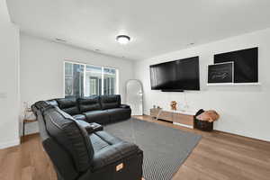 Living area with wood finished floors, visible vents, and baseboards
