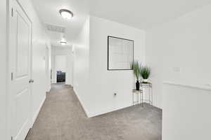 Corridor with carpet floors, baseboards, and visible vents
