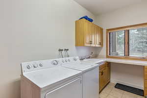 Washroom featuring washer and dryer, light tile patterned flooring, cabinet space, and a sink