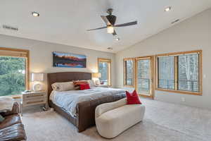 Bedroom with vaulted ceiling, multiple windows, and visible vents