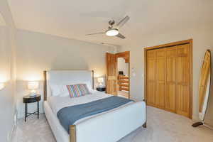 Bedroom with a closet, light carpet, and ceiling fan