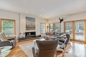 Living room featuring recessed lighting, light wood-type flooring, and a lit fireplace