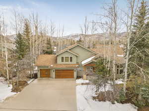 Rustic home with a mountain view, a garage, roof with shingles, and driveway