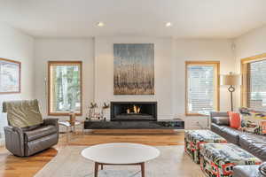 Living room featuring recessed lighting, wood finished floors, a wealth of natural light, and a lit fireplace