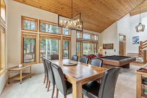 Dining room featuring light carpet, high vaulted ceiling, wood ceiling, and stairs