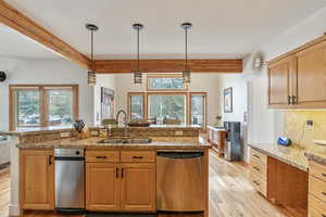 Kitchen with light wood finished floors, a sink, stainless steel dishwasher, beamed ceiling, and tasteful backsplash