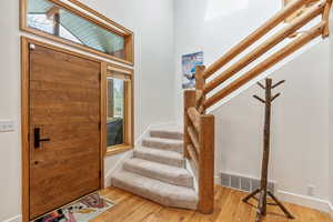 Entrance foyer with visible vents, baseboards, wood finished floors, and stairs