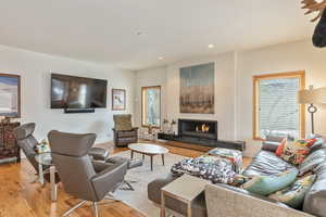 Living area with light wood-style floors, plenty of natural light, and a lit fireplace