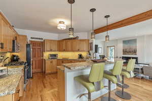 Kitchen featuring decorative backsplash, a kitchen breakfast bar, appliances with stainless steel finishes, and light wood-style flooring