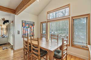 Dining area with light wood finished floors, vaulted ceiling with beams, and baseboards