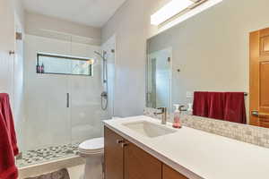 Full bath with vanity, toilet, a stall shower, and backsplash