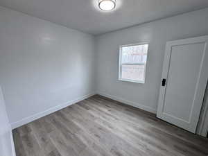 Spare room with a textured ceiling, wood finished floors, and baseboards