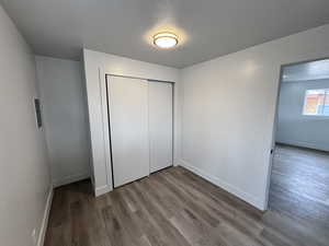 Unfurnished bedroom featuring a textured ceiling, baseboards, and wood finished floors