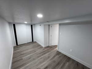 Finished basement featuring visible vents, a textured ceiling, baseboards, and wood finished floors