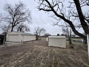 View of yard featuring an outbuilding, a detached garage, and dirt driveway