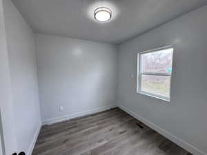 Unfurnished room with visible vents, a textured ceiling, baseboards, and wood finished floors