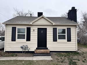 Bungalow with a shingled roof and a chimney