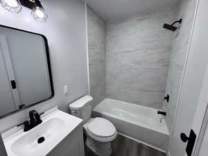 Full bathroom with toilet, bathtub / shower combination, wood finished floors, and vanity