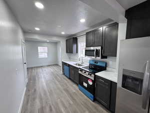 Kitchen featuring light wood-type flooring, appliances with stainless steel finishes, light countertops, and a sink