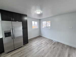 Unfurnished bedroom with visible vents, baseboards, light wood-style floors, a closet, and stainless steel fridge