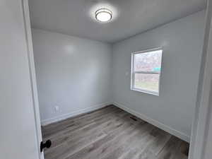 Unfurnished room featuring visible vents, a textured ceiling, baseboards, and wood finished floors