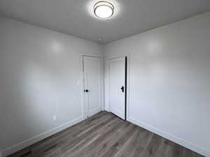 Spare room with a textured ceiling, baseboards, and wood finished floors