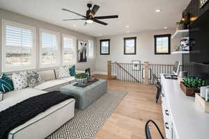 Living area featuring light wood finished floors, baseboards, a ceiling fan, and recessed lighting