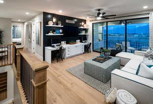 Living room with recessed lighting, ceiling fan, built in desk, and light wood finished floors