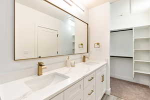 Bathroom featuring double vanity, baseboards, and a sink