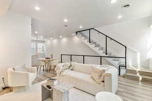 Living area featuring baseboards, visible vents, stairs, light wood-type flooring, and recessed lighting